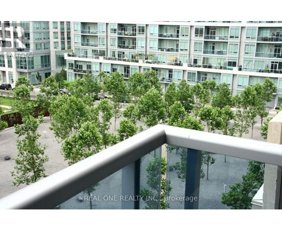 A balcony overlooks a courtyard with trees and a building in the background.