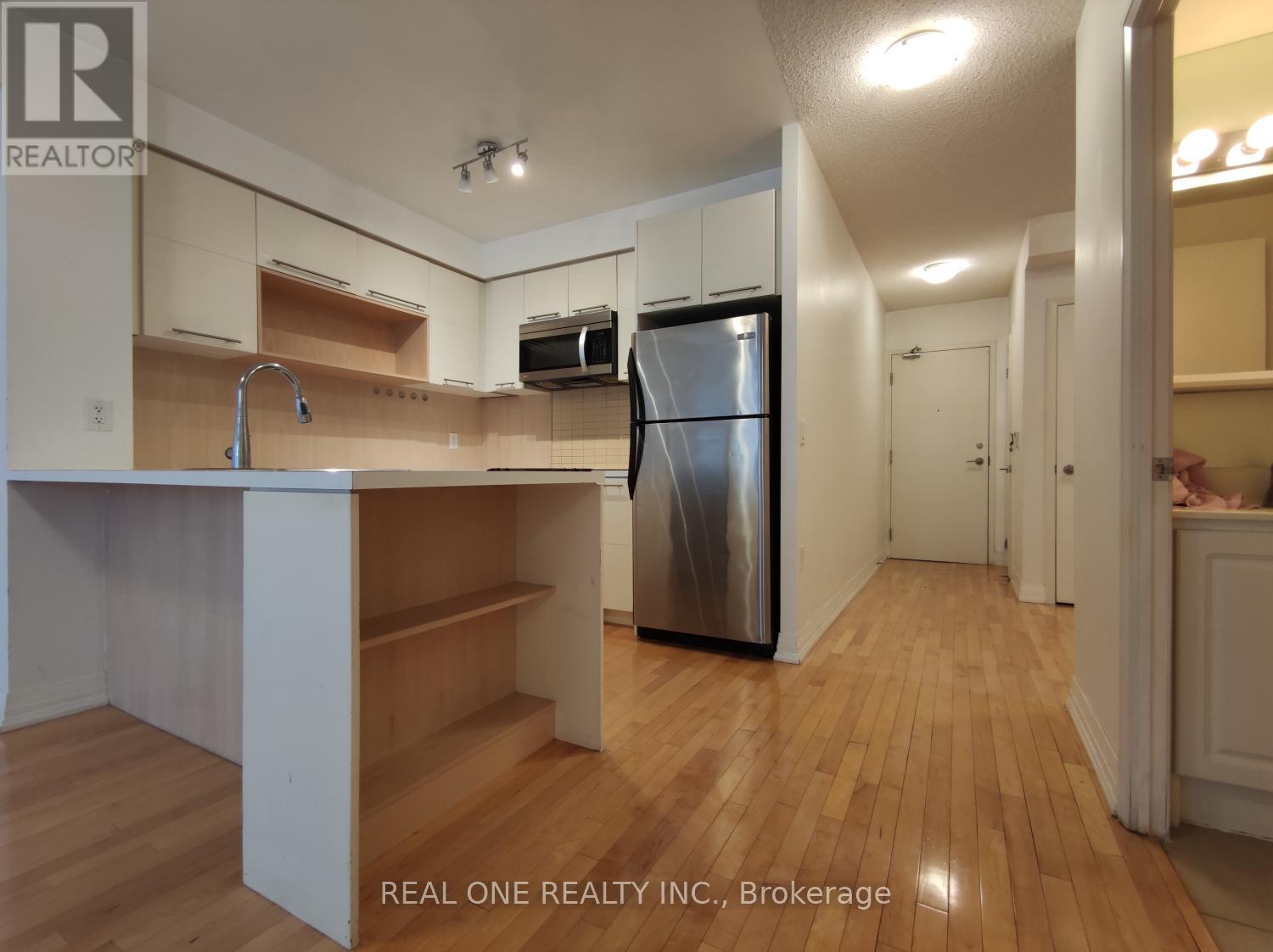 A kitchen with a refrigerator, sink, and cabinets.
