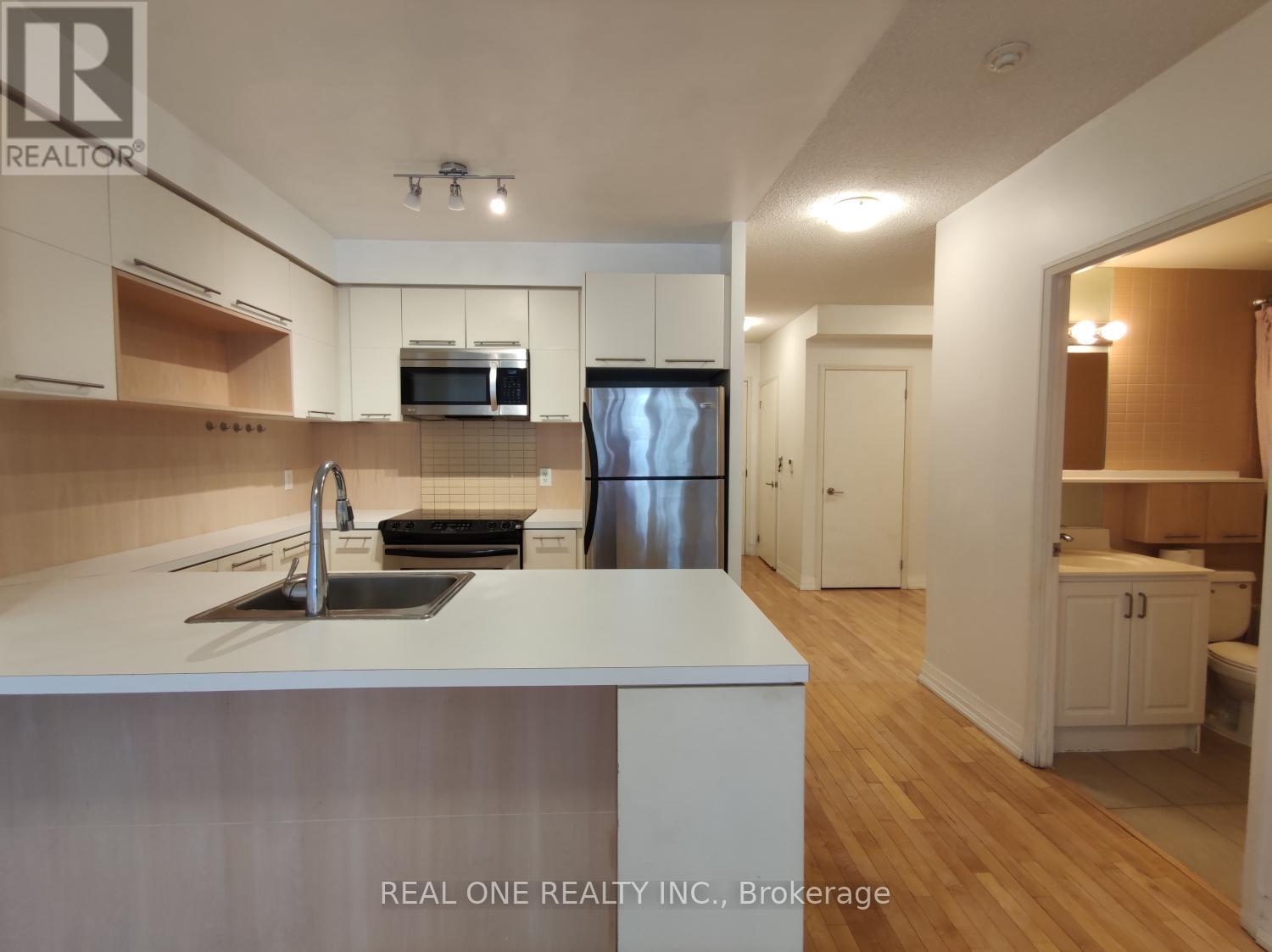 A kitchen with white countertops and wooden floors.
