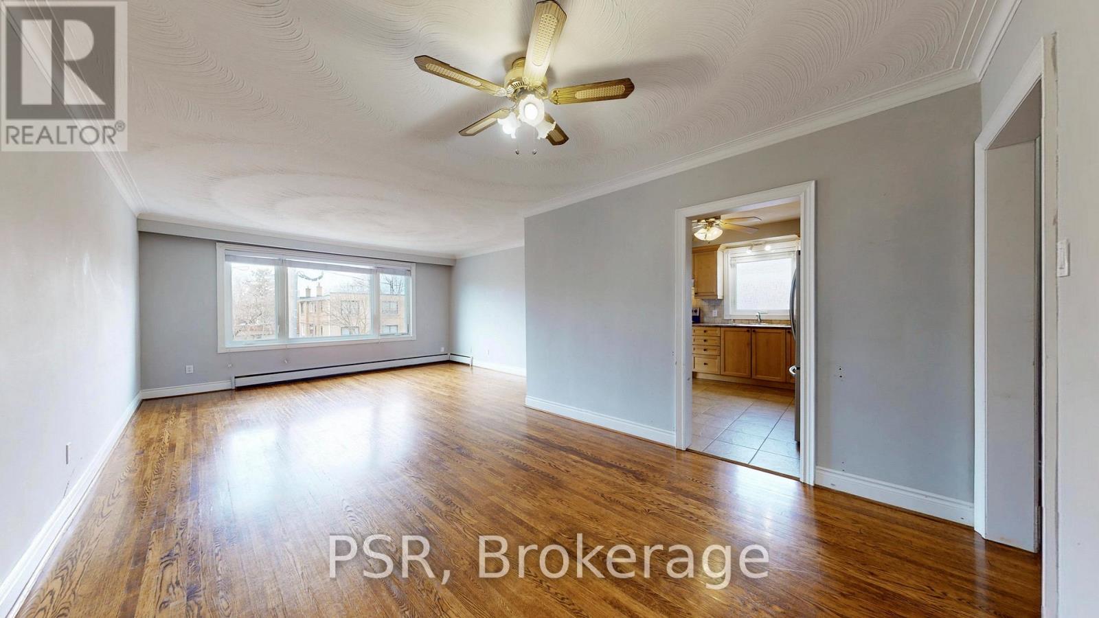 A spacious room with a ceiling fan and wooden flooring.