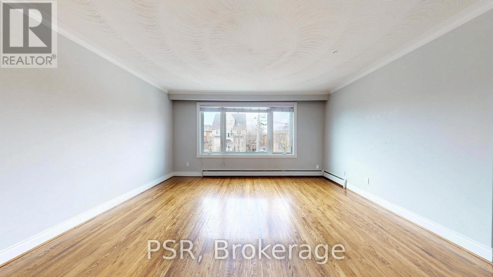A large, empty room with wooden floors and a window.