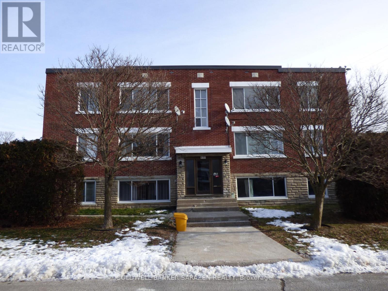 A brick building with a snow bank in front.