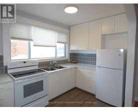 A white kitchen with a refrigerator, stove, and sink.