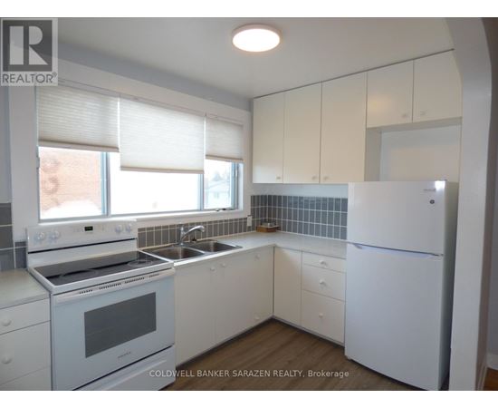 A white kitchen with a refrigerator, stove, and sink.