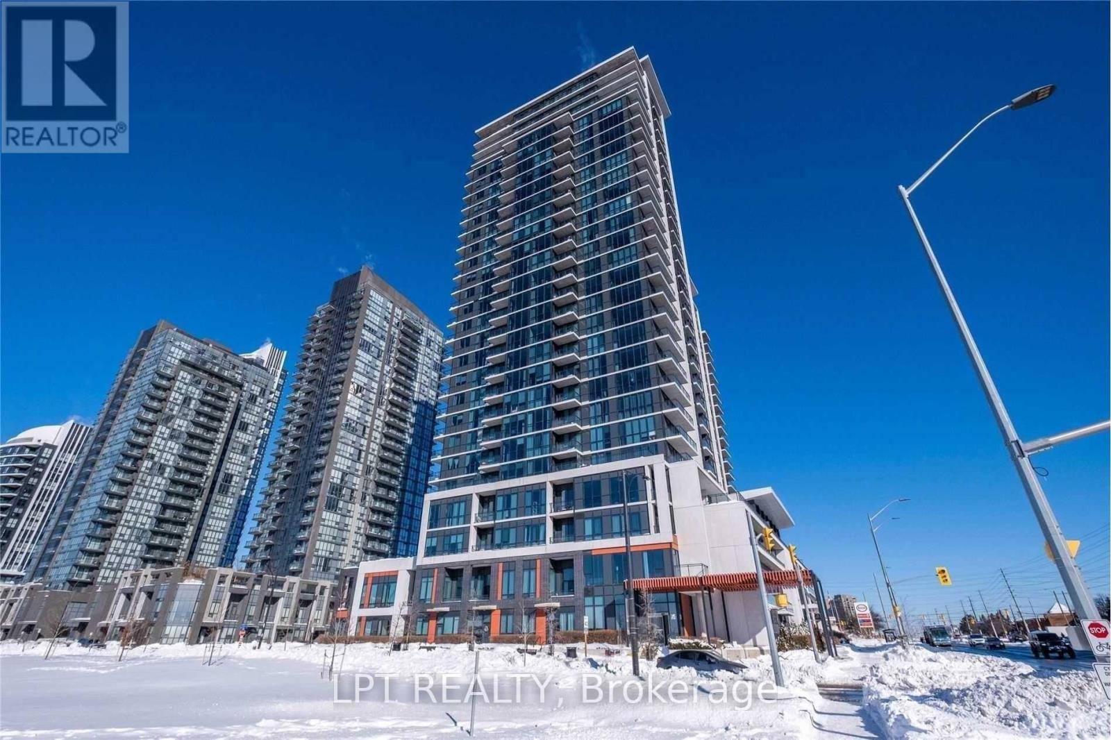 A tall building with many windows is in the foreground with a blue sky in the background.