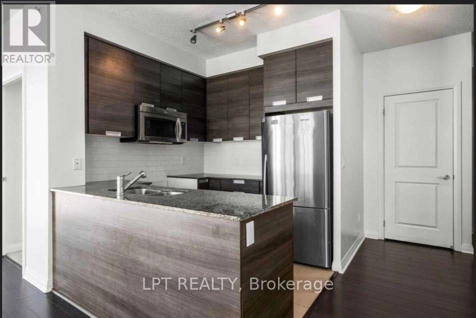 A modern kitchen with a stainless steel refrigerator and microwave.