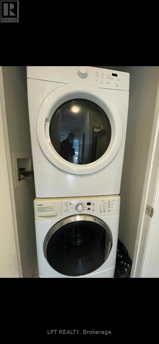 A white washing machine with a black door is in a small space.