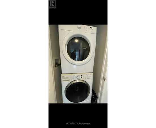 A white washing machine with a black door is in a small space.