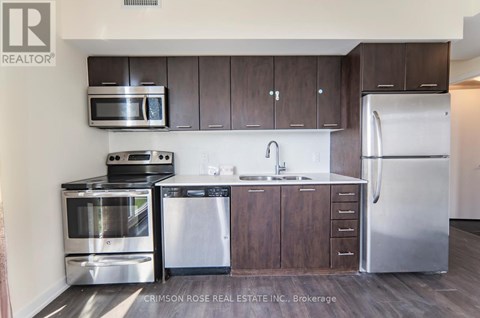 A kitchen with dark wood cabinets and stainless steel appliances.