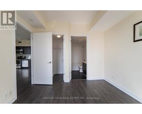 A real estate listing photo of a white bedroom with a white door and a white toilet.