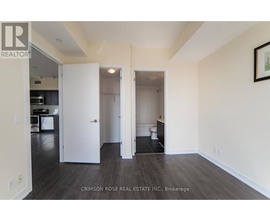 A real estate listing photo of a white bedroom with a white door and a white toilet.