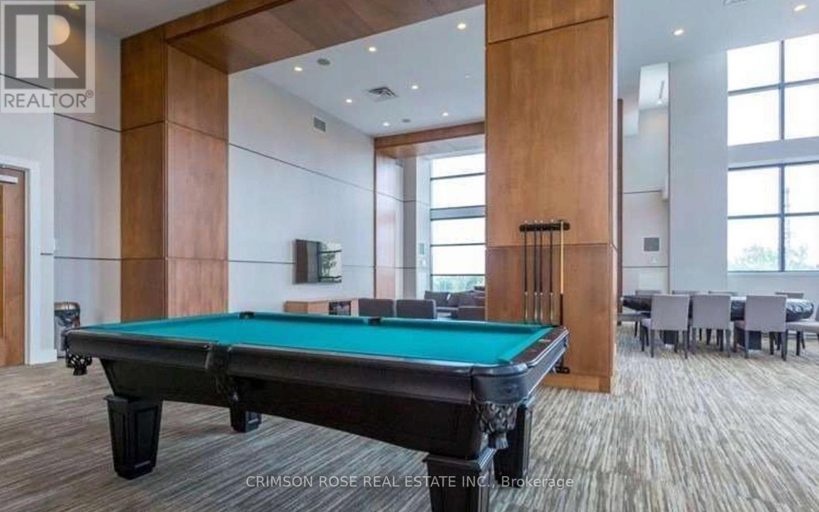 A pool table in a room with a brokerage logo.
