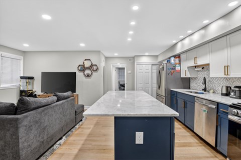 A modern kitchen with a grey couch and a marble island.