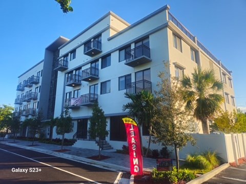 A tall white building with balconies and a red sign that says "GALAXY S23+".