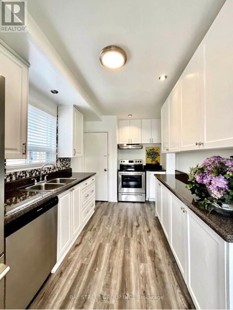 A kitchen with white cabinets and a wooden floor.
