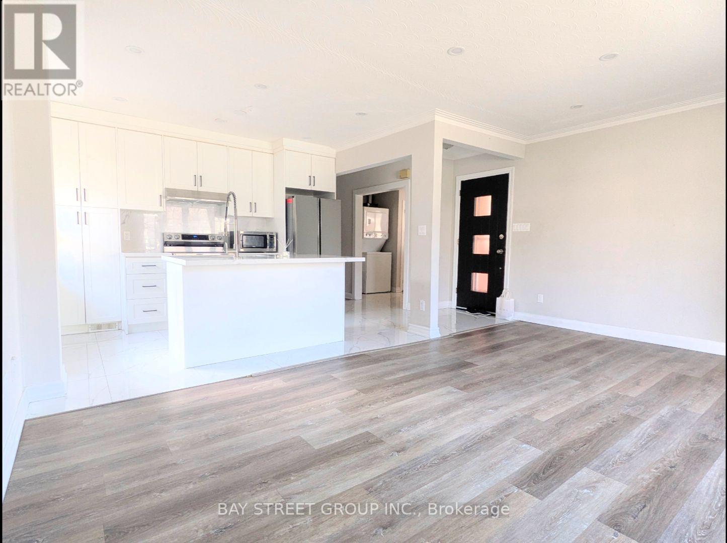 A spacious kitchen with white cabinets and a wooden floor.