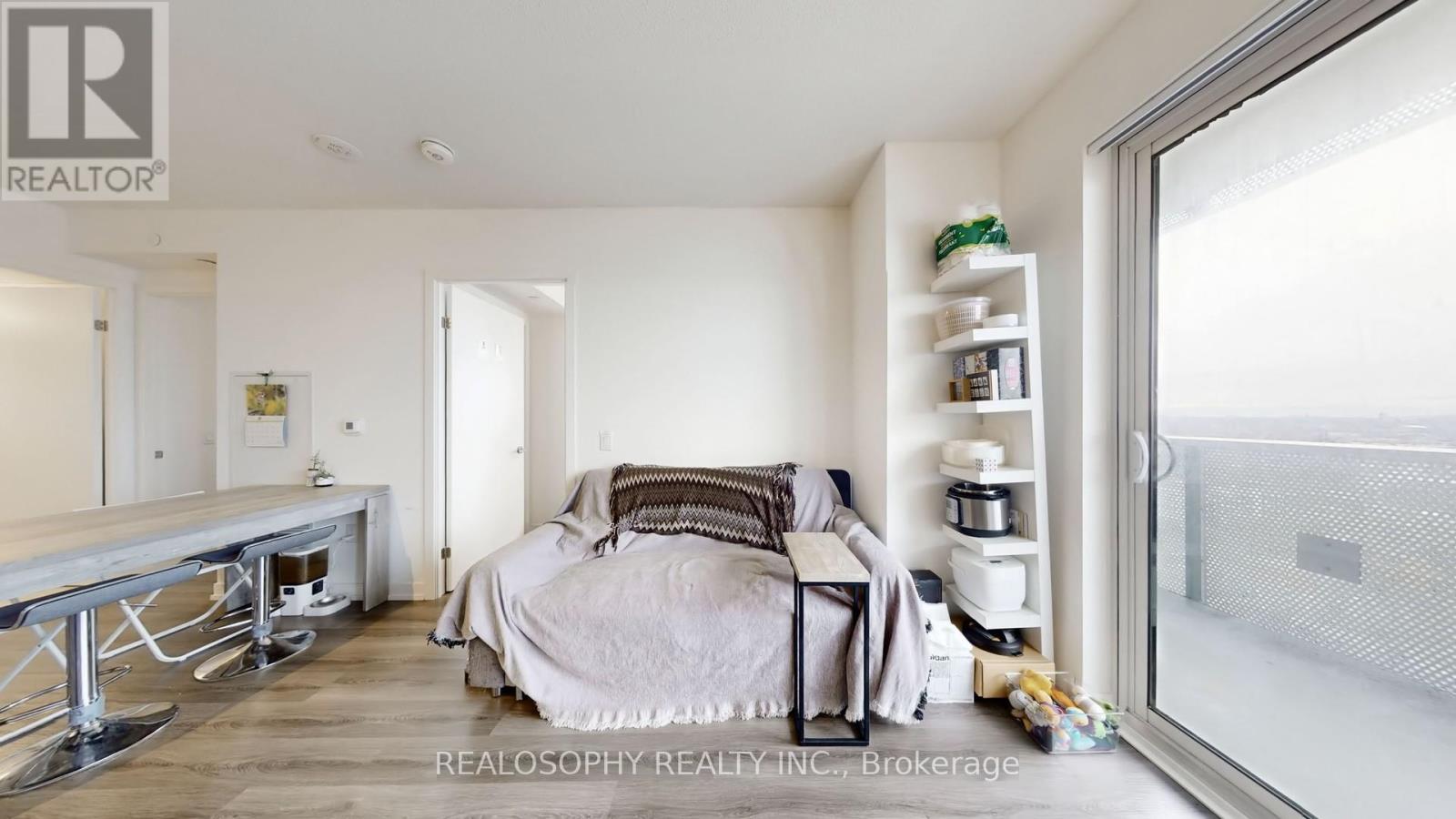 A bedroom with a bed, nightstand, and a window with a view of the outside.