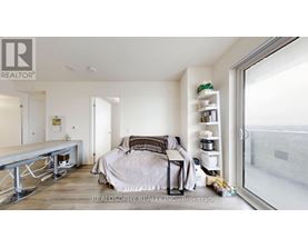 A bedroom with a bed, nightstand, and a window with a view of the outside.