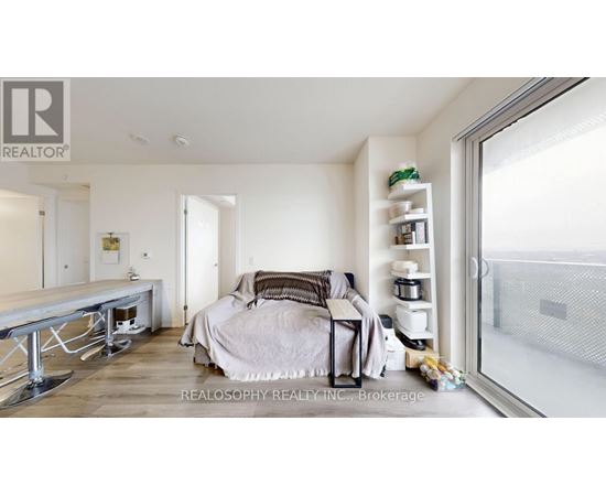 A bedroom with a bed, nightstand, and a window with a view of the outside.