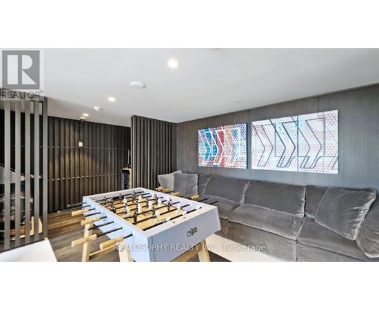 A modern living room with a foosball table and grey couch.