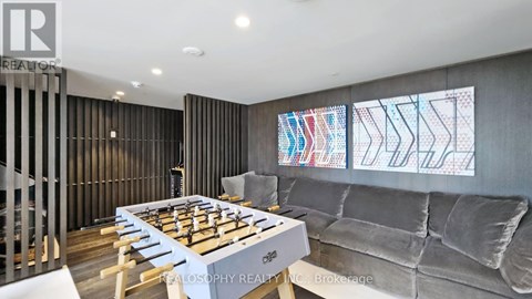 A modern living room with a foosball table and grey couch.