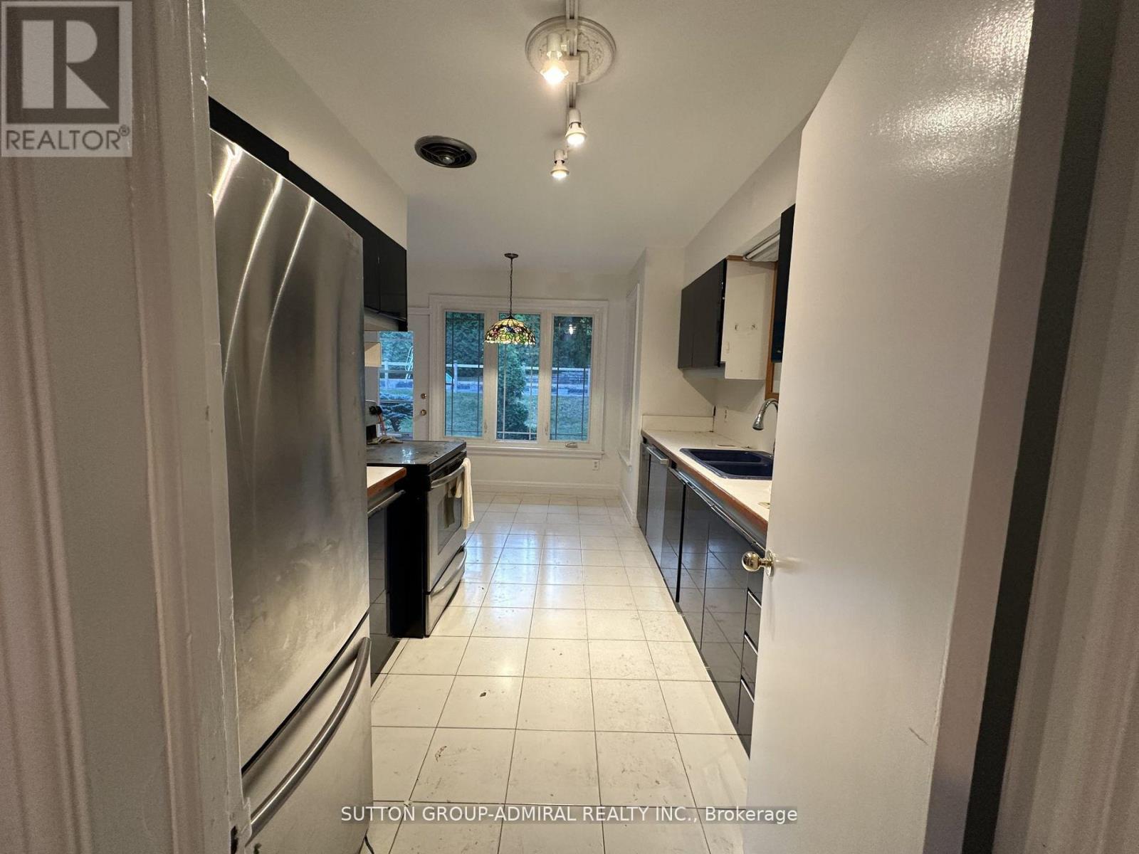 A kitchen with white tiled floors and a stainless steel refrigerator.