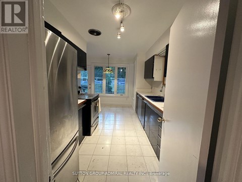 A kitchen with white tiled floors and a stainless steel refrigerator.