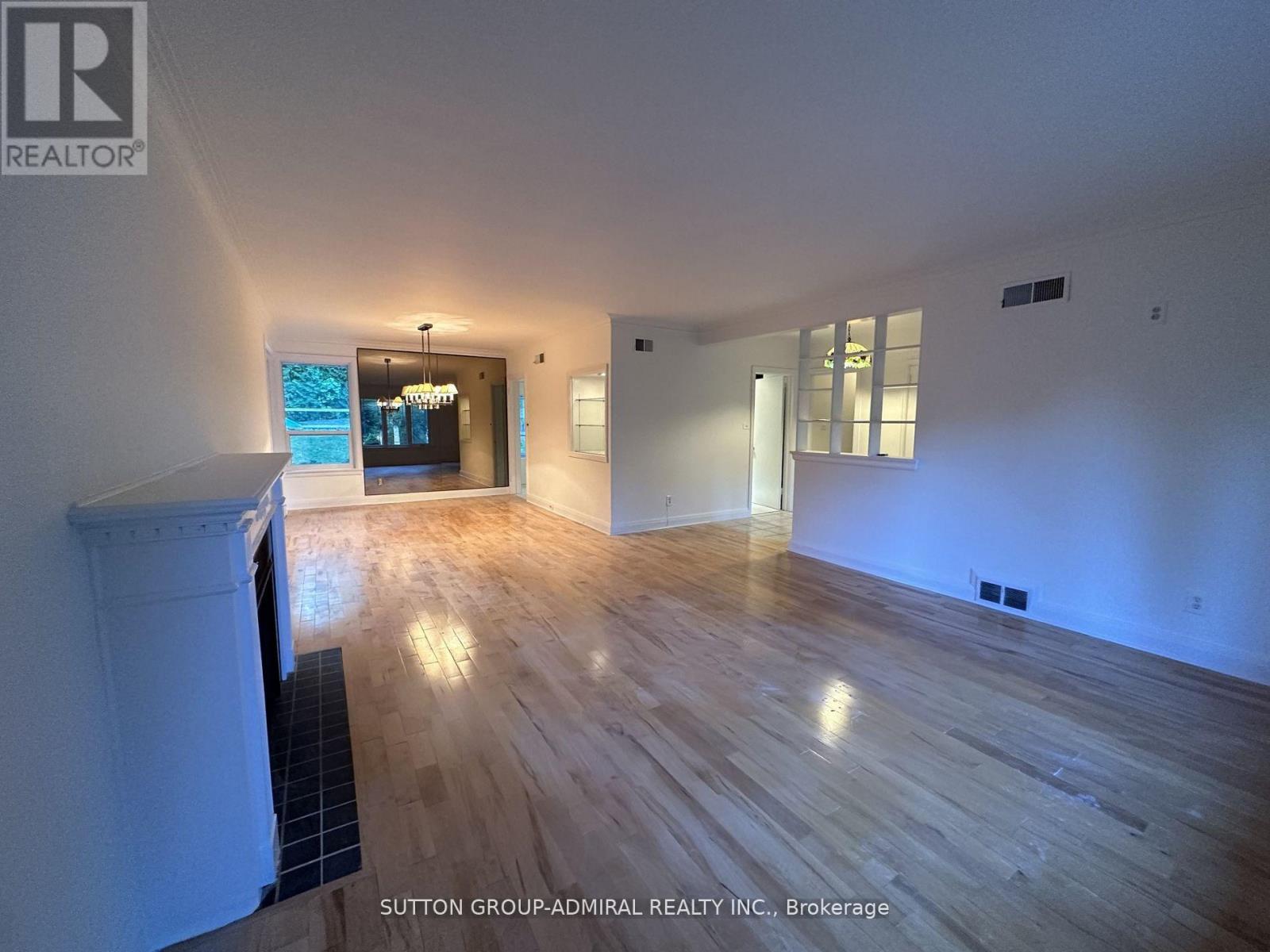 A spacious room with wooden flooring and white walls.