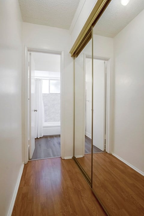 A hallway with white walls and wood flooring.