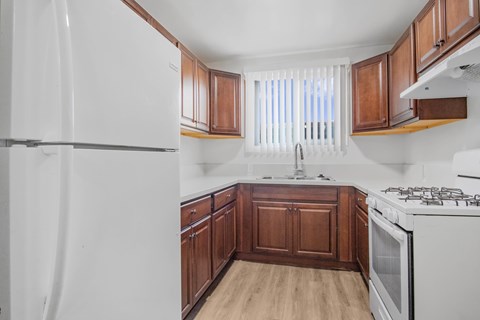 A kitchen with white appliances and wooden cabinets.