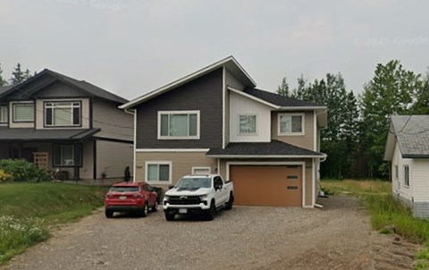 Two cars are parked in front of a two-story house.