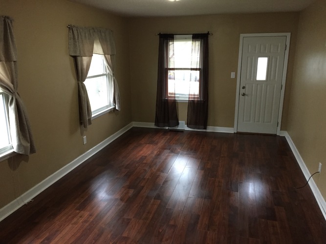 A room with brown wooden floors and a white door.