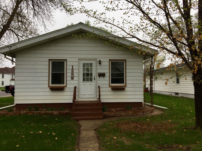 A small white house with a brown door and windows.