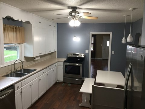 A kitchen with white cabinets and a stainless steel refrigerator.