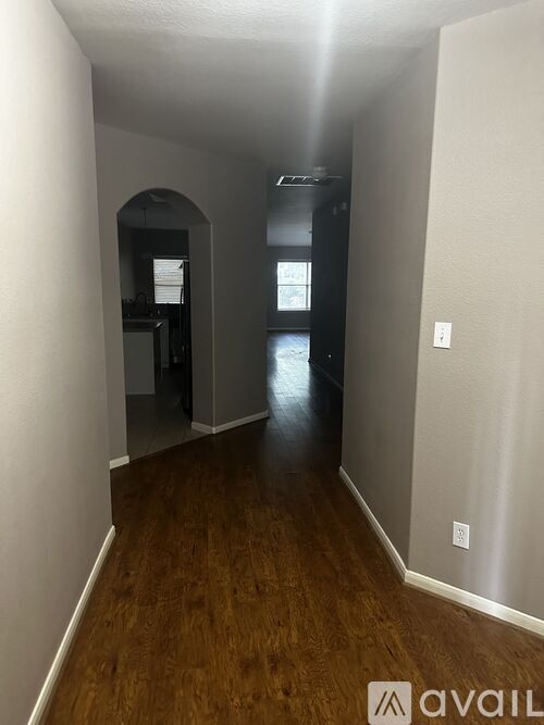 A long hallway with wood floors and a white wall on the left.