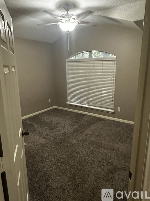 A room with a ceiling fan and carpeted floor.