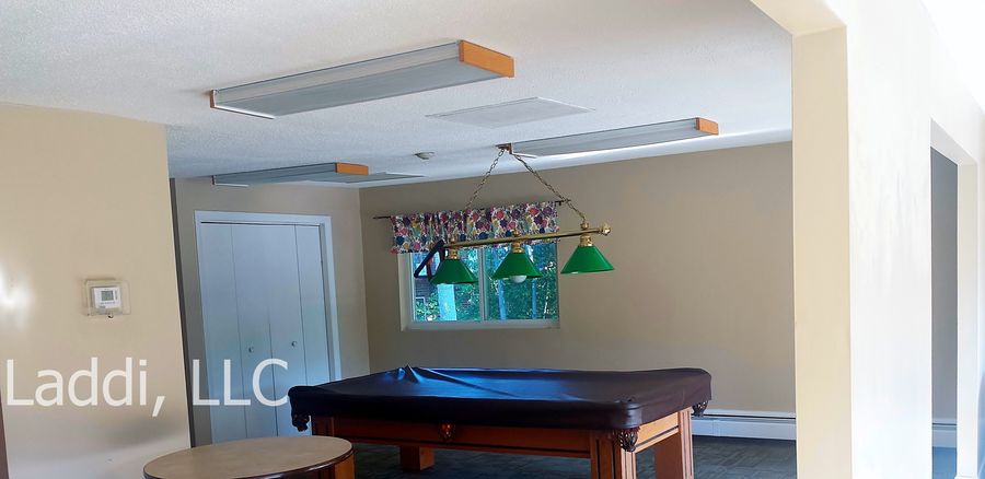 A room with a pool table and a sign that says Laddi, LLC.