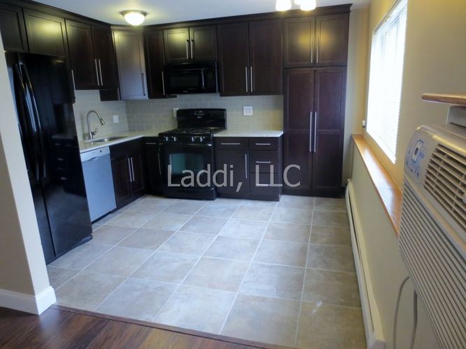 A kitchen with black cabinets and a tile floor.