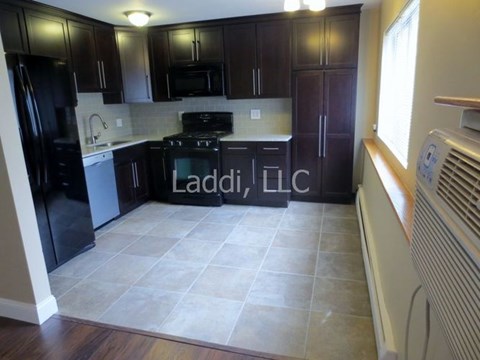 A kitchen with black cabinets and a tile floor.