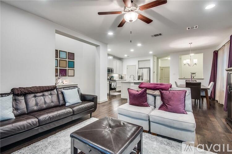 A living room with a brown leather couch and a white sofa with purple pillows.