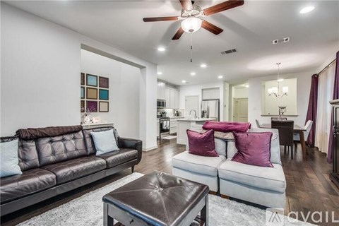A living room with a brown leather couch and a white sofa with purple pillows.