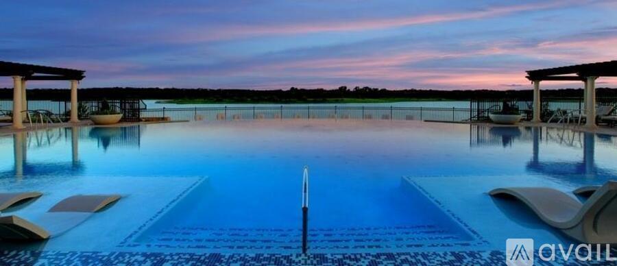 A large outdoor swimming pool with a beautiful sunset in the background.