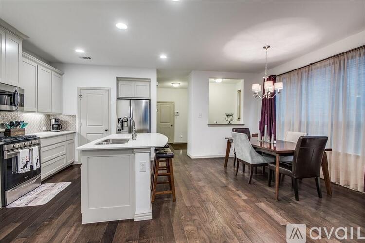 A modern kitchen with white cabinets and a wooden floor.