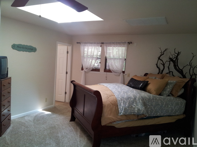 A bedroom with a bed, dresser, and window.
