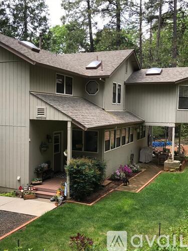 A house with a grey siding and a brown roof with a patio and a pool table.