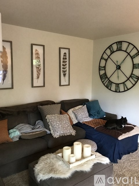 A living room with a couch, a table with candles, and a clock on the wall.