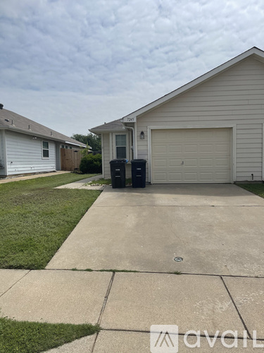 A house with a driveway and a trash can in front of it.