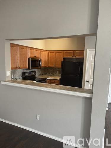 A kitchen with wooden cabinets and a black refrigerator.