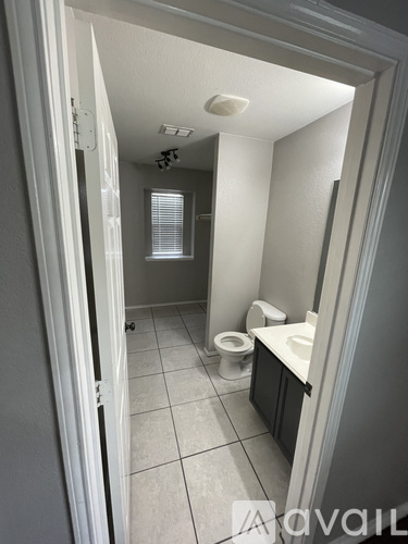 A bathroom with a toilet, sink, and mirror.