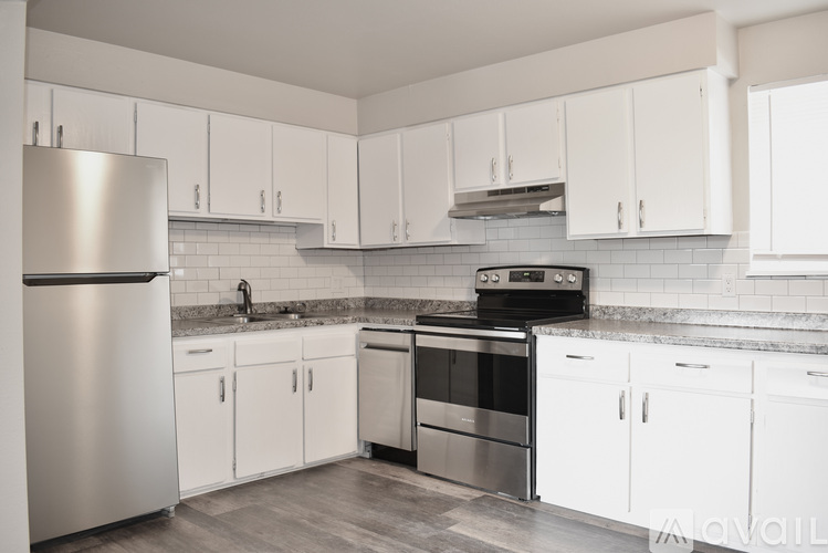 A kitchen with white cabinets and a stainless steel refrigerator.